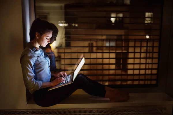 Een vrouw die werken op een laptop bij nacht. — Stockfoto