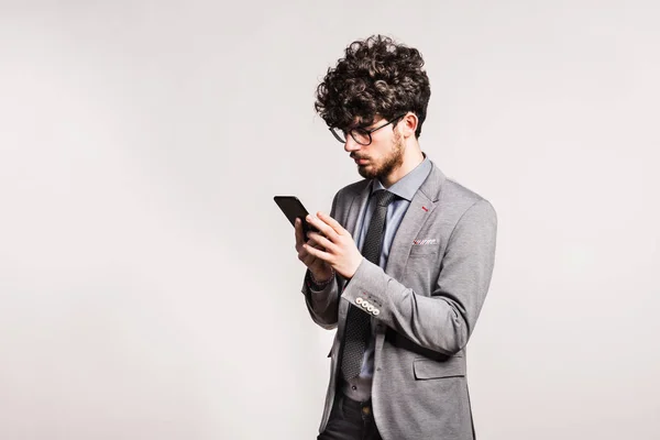 Portrait of a young man with smartphone in a studio. — Stock Photo, Image