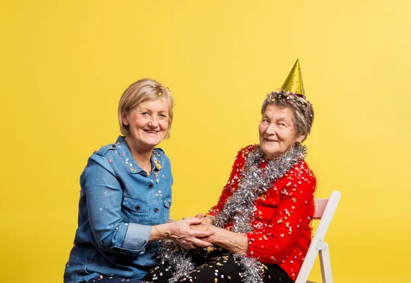 Retrato de una mujer mayor en el estudio sobre un fondo amarillo. Concepto del partido . — Foto de Stock