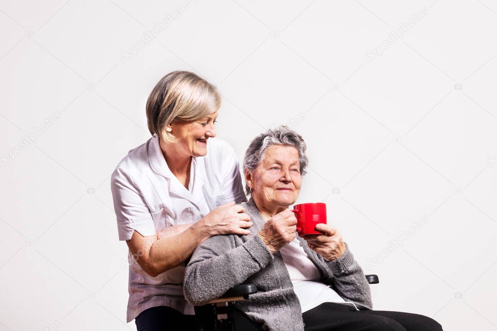 Studio portrait of a senior woman in wheelchair and a nurse.