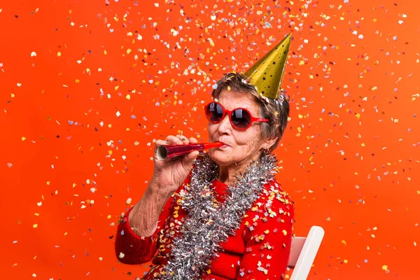 Portrait of a senior woman in studio on a red background. Party concept. — Stock Photo, Image