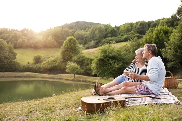 Pareja mayor en el lago haciendo un picnic . — Foto de Stock