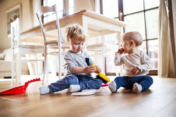 Zwei Kleinkinder mit Pinsel und Kehrschaufel zu Hause. — Stockfoto