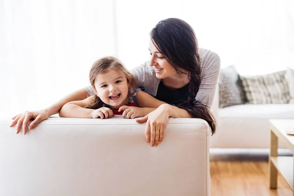 Jovem mãe com uma menina pequena em casa . — Fotografia de Stock