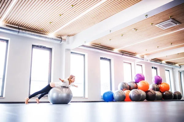 Genç kadın bir spor salonunda bir fitball ile egzersiz yaparak. — Stok fotoğraf
