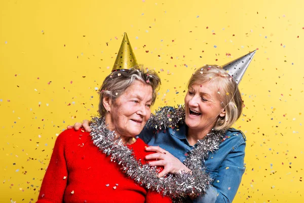 Portrait of a senior women in studio on a yellow background. Party concept. — Stock Photo, Image