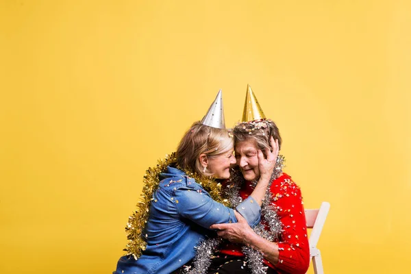 Portret van een senior vrouwen in studio op een gele achtergrond. Party concept. — Stockfoto