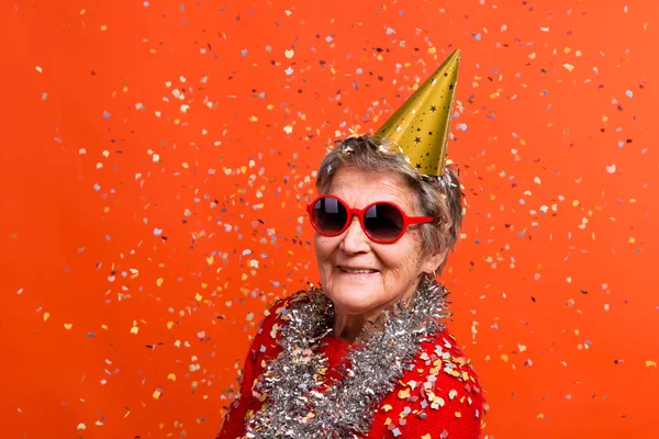 Portrait d'une femme âgée en studio sur fond rouge. Concept de parti . — Photo