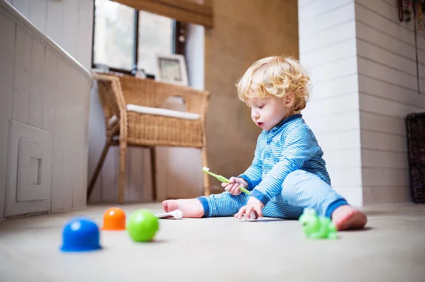 Toddler boy with toothbrush sitting on the floor in the bathroom. — Stock Photo, Image