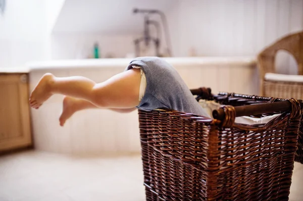 Un niño pequeño en una cesta de lavandería, las piernas sobresaliendo . —  Fotos de Stock