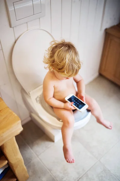 Menino bonito da criança com smartphone no banheiro . — Fotografia de Stock