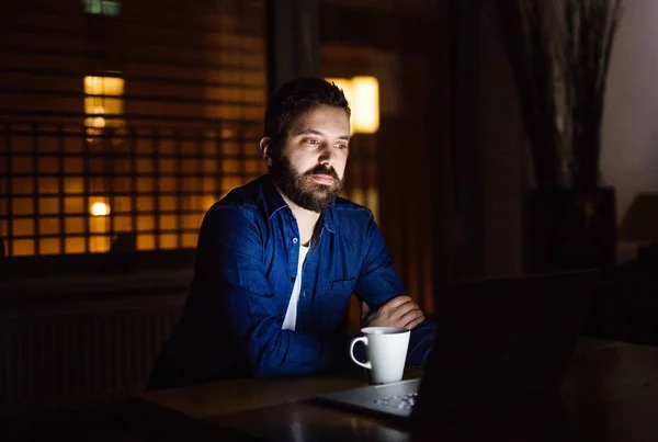 Człowiek pracuje na laptopie w domu w nocy. — Zdjęcie stockowe