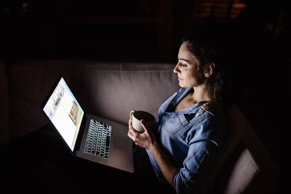 Een vrouw die werken op een laptop bij nacht. — Stockfoto