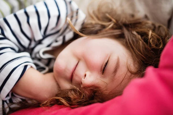 Una pequeña chica feliz en camiseta a rayas en casa durmiendo . — Foto de Stock