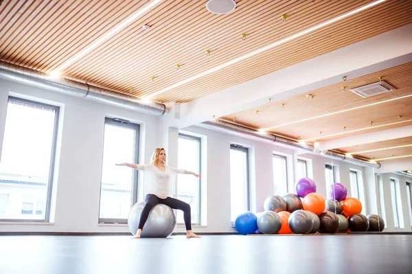 Genç kadın bir spor salonunda bir fitball ile egzersiz yaparak. — Stok fotoğraf