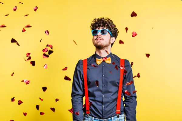 Portret van een jonge man met zonnebril in een studio op een gele achtergrond. — Stockfoto