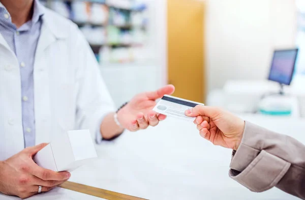 Cliente irriconoscibile che dà una carta di credito a un farmacista maschio . — Foto Stock