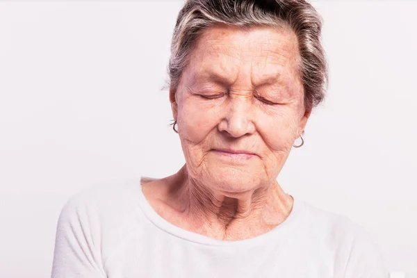 Portret senior kobiety z zamkniętymi oczami w studio. — Zdjęcie stockowe