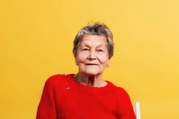 Porträtt av en äldre kvinna i studion på gul bakgrund. — Stockfoto