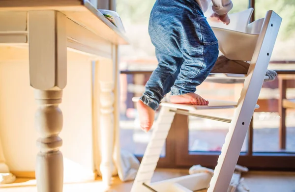 Jongen van de peuter in een gevaarlijke thuis, klimmen in de hoge stoel. — Stockfoto