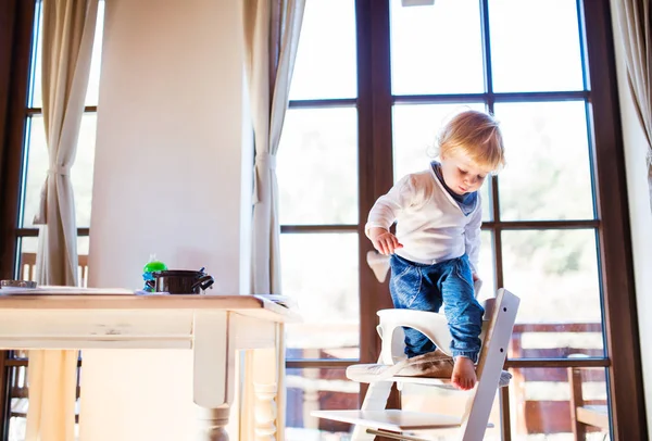 Μικρό παιδί αγόρι σε μια επικίνδυνη στο σπίτι, αναρρίχηση στο καρεκλάκι. — Φωτογραφία Αρχείου