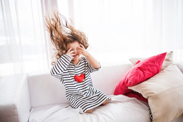 Una pequeña chica feliz en camiseta a rayas en casa divirtiéndose . — Foto de Stock