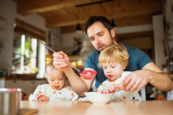 Father feeding two toddlers at home. — Stock Photo, Image