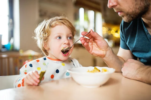 Отец кормит маленького мальчика дома . — стоковое фото