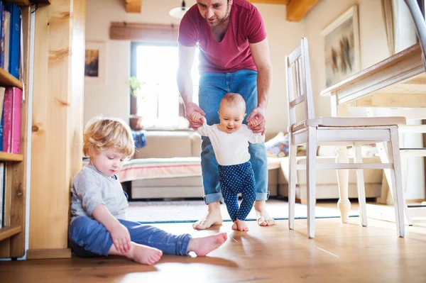 Vater mit zwei Kleinkindern zu Hause. Erste Schritte. — Stockfoto