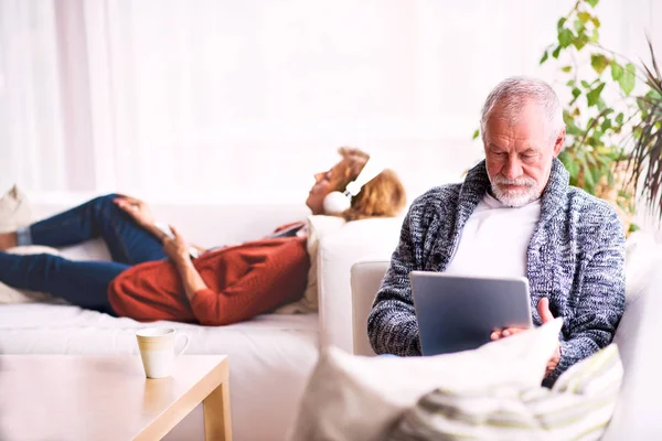 Seniorenpaar mit Tablet und Kopfhörer entspannt zu Hause. — Stockfoto