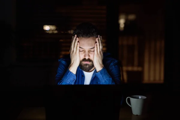 Um homem cansado com laptop em casa à noite . — Fotografia de Stock