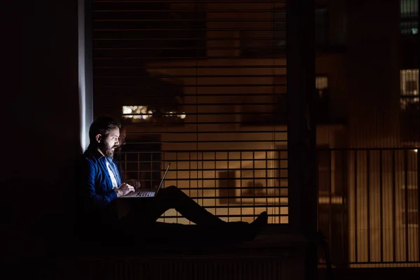Człowiek pracuje na laptopie w domu w nocy. — Zdjęcie stockowe