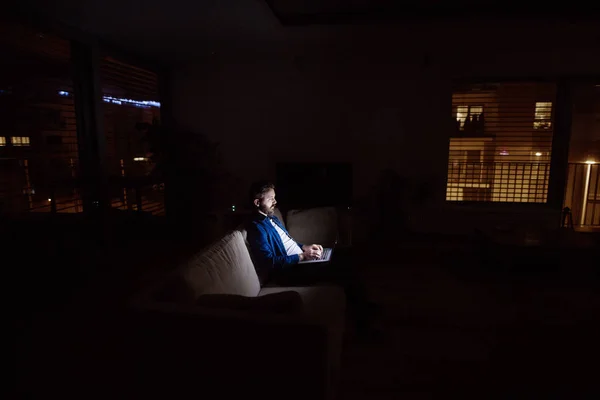 Un hombre trabajando en un portátil en casa por la noche . —  Fotos de Stock