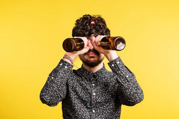 Studio portret van een jonge man die flessen op een gele achtergrond. — Stockfoto