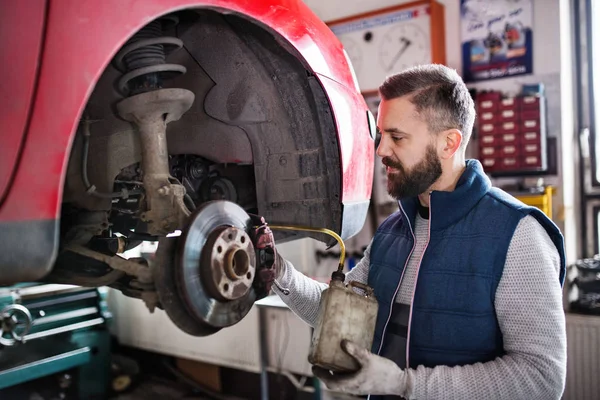 Hombre mecánico reparación de un coche en un garaje. —  Fotos de Stock