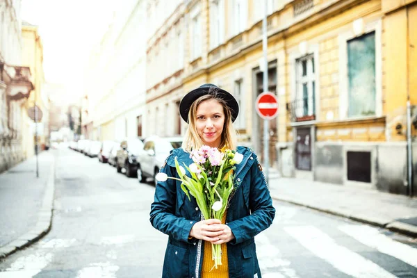 Jovem mulher com flores na cidade de primavera ensolarada . — Fotografia de Stock