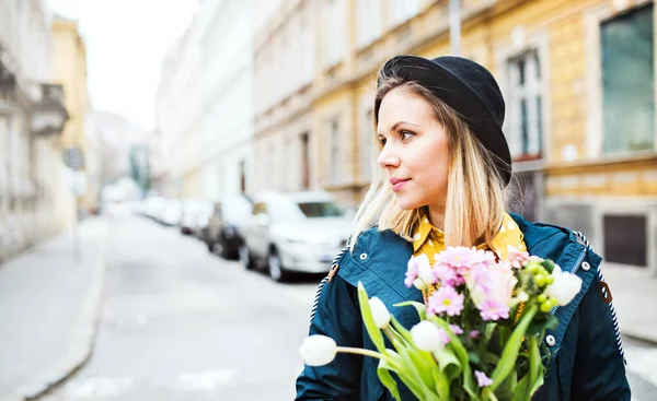 Jonge vrouw met bloemen in zonnige lente stad. — Stockfoto