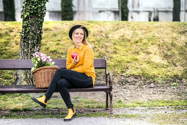 Junge Frau mit Blumen in einem Korb in der sonnigen Frühlingsstadt. — Stockfoto