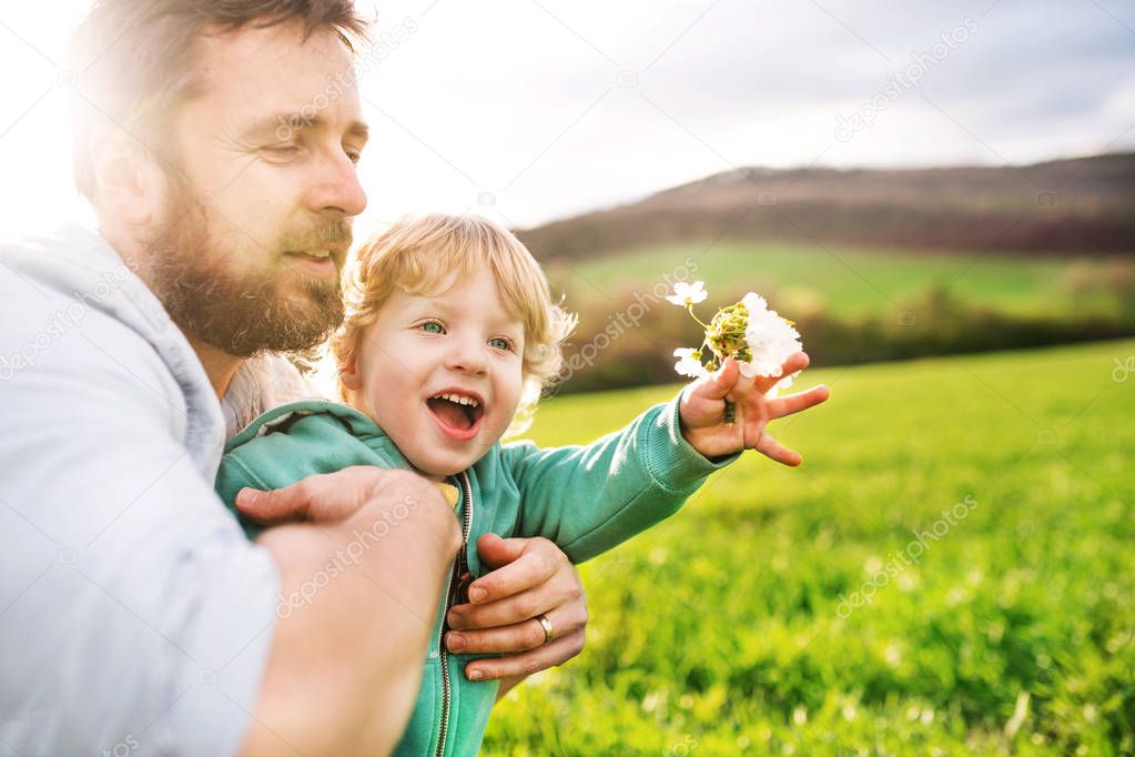 A father with his toddler son outside in spring nature.