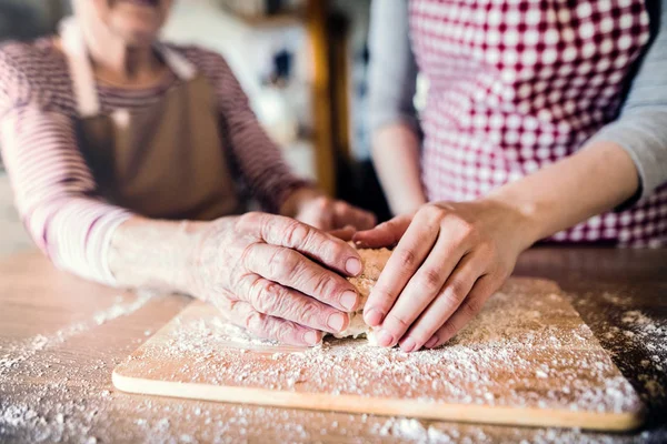 Vanhempi isoäiti, jolla on aikuinen lapsenlapsi kotona, leivonta . — kuvapankkivalokuva