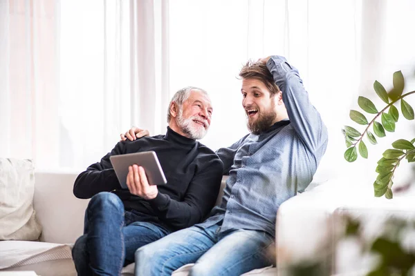 Hipster son and his senior father with tablet at home. — Stock Photo, Image