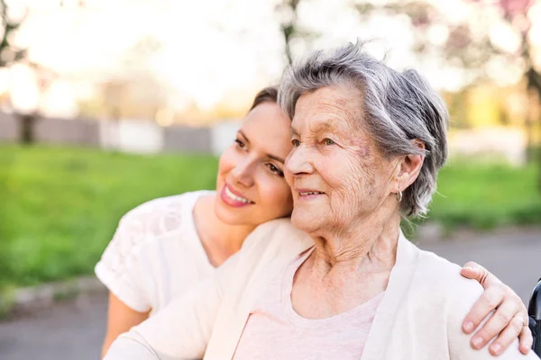 Elderly grandmother and granddaughter hugging in spring nature. — Stock Photo, Image