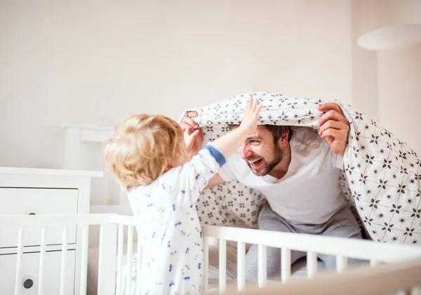 Vater mit einem kleinen Jungen, der zu Hause im Schlafzimmer vor dem Schlafengehen Spaß hat. — Stockfoto