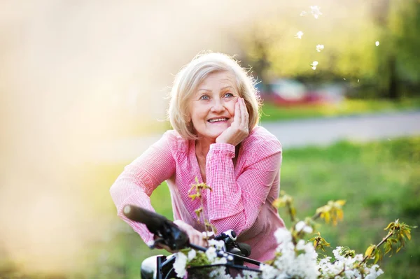 Hermosa mujer mayor con bicicleta fuera en la naturaleza de primavera . — Foto de Stock