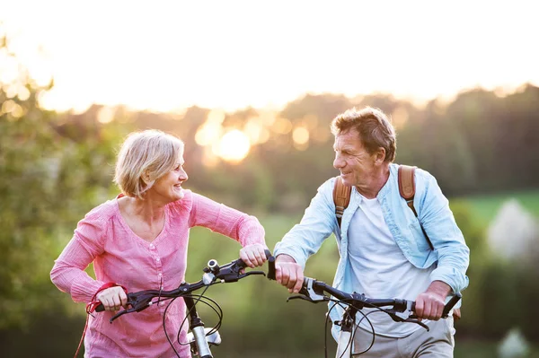 Vacker äldre par med cyklar utanför i vår natur. — Stockfoto