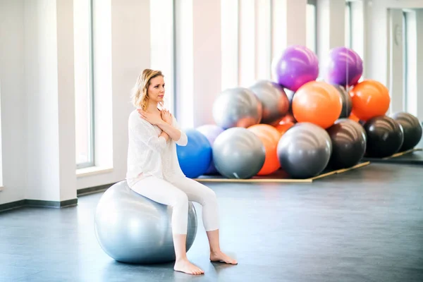 Junge Frau turnt mit einem Fitball in einem Fitnessstudio. — Stockfoto