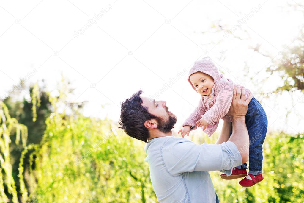 A father with his toddler daughter outside in spring nature.