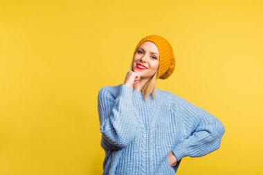 Studio sarı bir arka plan üzerine yün şapka olan güzel bir kadın portresi.