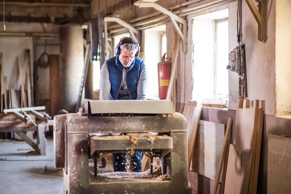 Un homme ouvrier dans l'atelier de menuiserie, travaillant le bois . — Photo