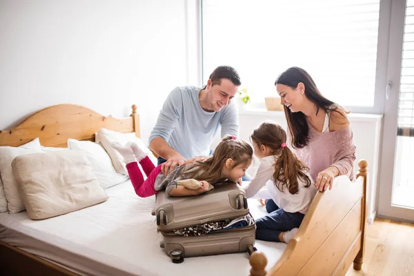 Mladá rodina se dvěma dětmi balení pro dovolenou. — Stock fotografie